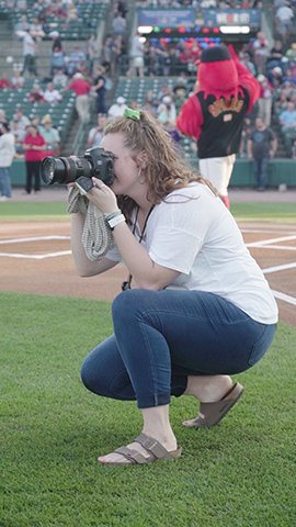 Amelia Hamilton taking photographs at a baseball game.