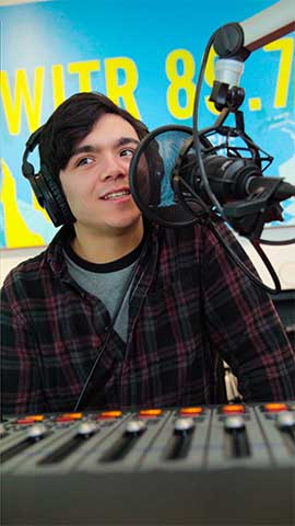 Nate Bellavia (DJ Nathaniel Rochester) talking into a mic while working as a DJ.