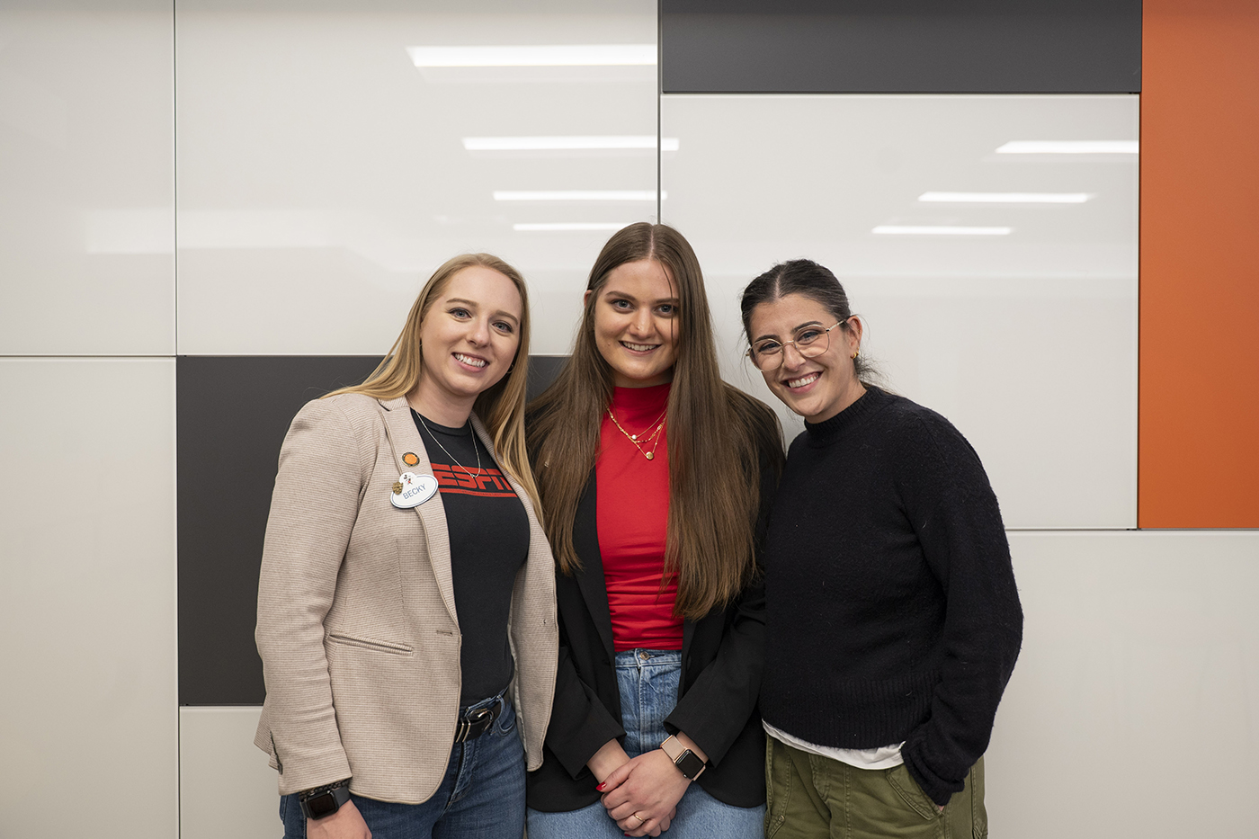 A trio of alumni stand next to each other on the RIT campus.
